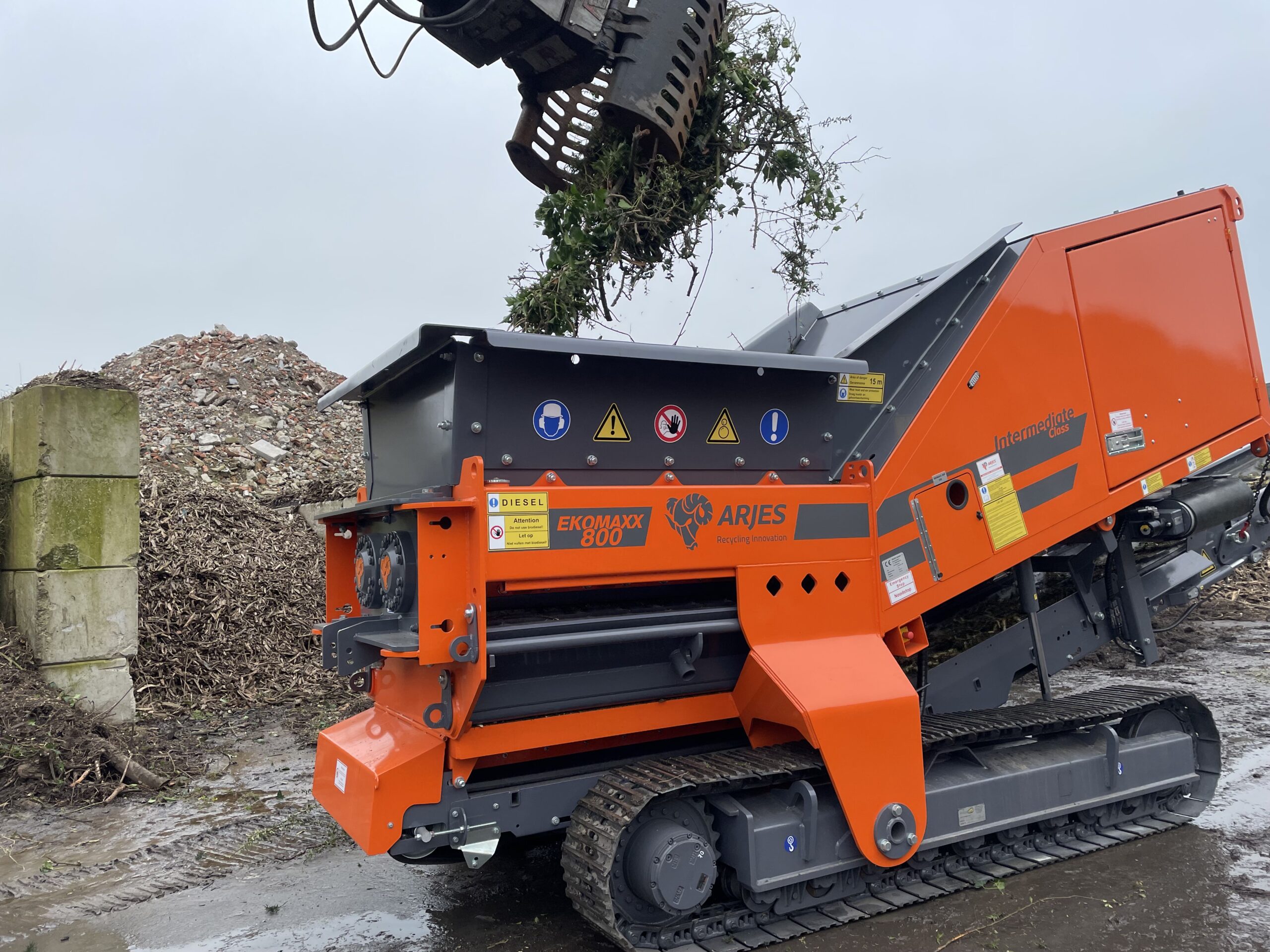 Groenafval wordt met behulp van een kraan in de versnipperingskamer van de Arjes Ekomaxx 800 gebracht.